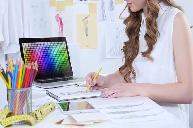 Styliste utilisant un logiciel de création assistée par ordinateur pour dessiner des modèles de mode.