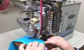 Machine de collage par ultrason utilisée pour assembler des pièces de tissu bleu.